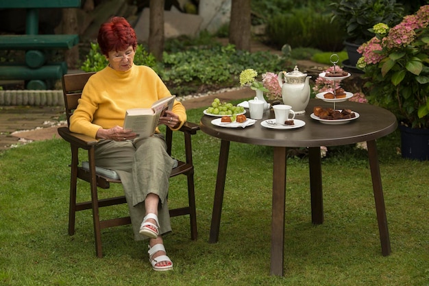 Photo senioren woman sitting in the garden and reading a book