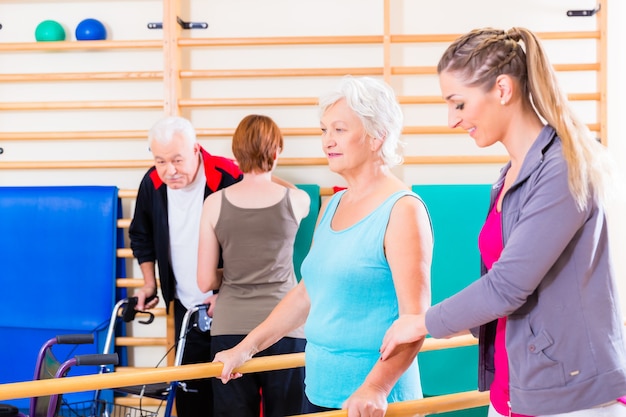 Seniors in physical rehabilitation therapy with trainer