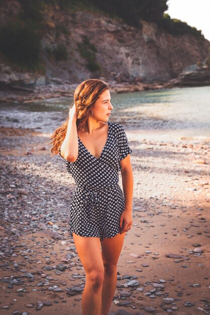 Sensual girl in a rocky cove wearing a black and white dots dress