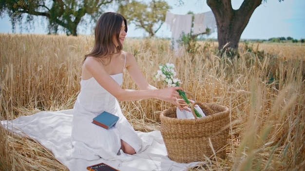 Sensual girl sniffing flowers on summer picnic lady taking bouquet from basket