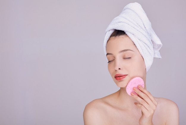 Sensual woman holds a sponge near the face.