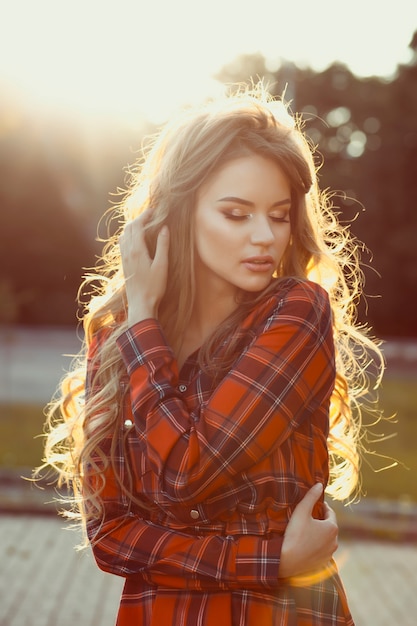 Sensual young model with closed eyes in checkered dress in rays of sun