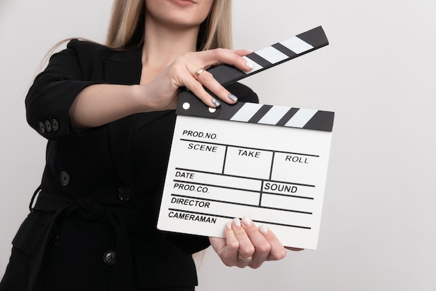 Sensuality beautiful woman with long hair dressed in black suit in studio holding clapperboard