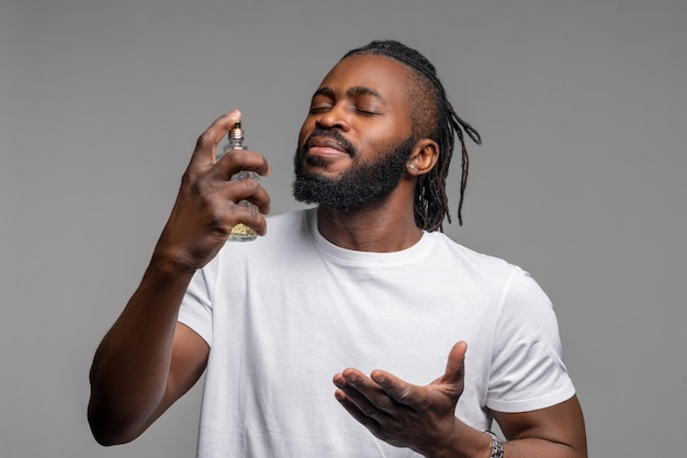 Serene African American guy spritzing himself with cologne