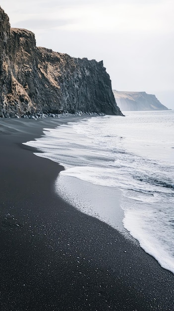 A serene black sand beach with crashing waves against rugged Icelandic coastline