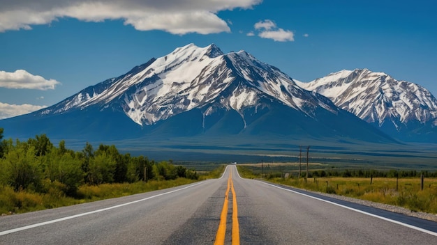 A serene road leading towards snow capped mountains at sunset