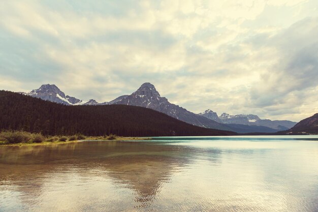 Serene scene by the mountain lake in Canada with reflection of the rocks in the calm water.