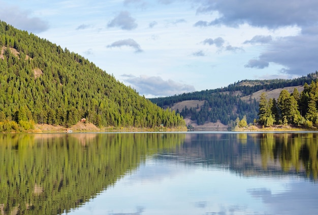 Serene scene by the mountain lake with reflection of the rocks in the calm water.