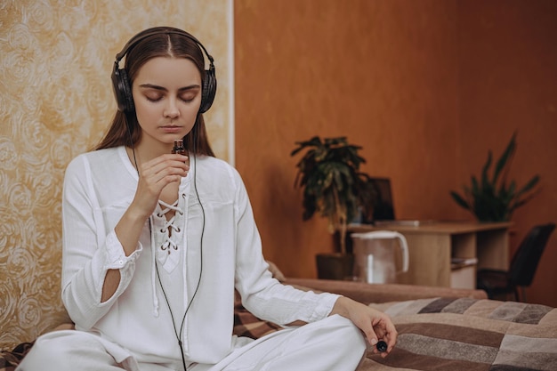 Serene woman in earphones listening to music and doing aromatherapy with essential oil