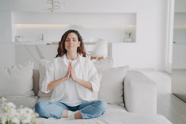 Serene young latin woman practicing yoga and posture exercise lotus asana at home