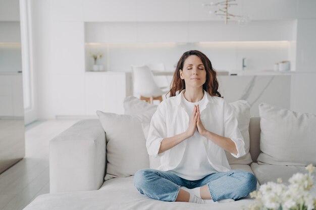 Serene young latin woman practicing yoga and posture exercise lotus asana at home