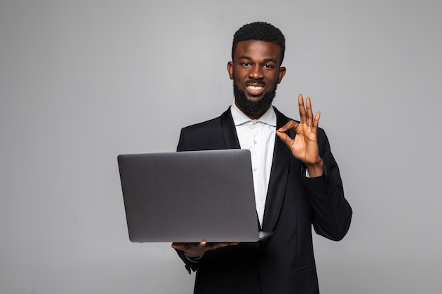 Serious African American businessman holding laptop computer with okay sign