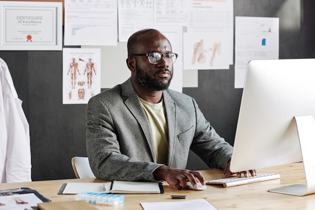 Serious african businessman working on computer at his workplace at office