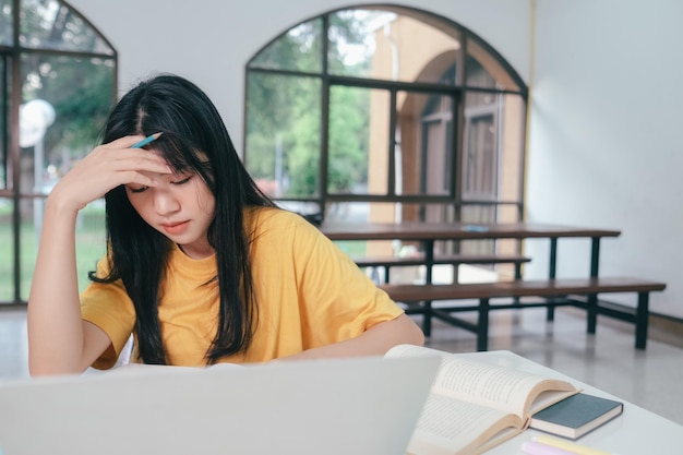 Serious Asian female student reading books for exam preparation