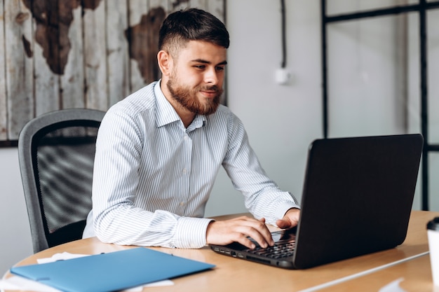 Serious, bearded man working on a computer in the office