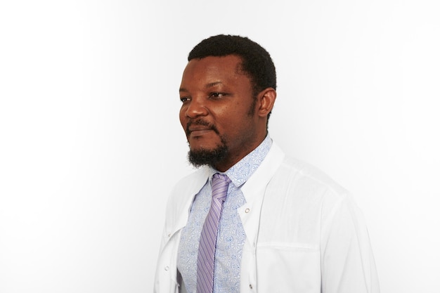 Serious black doctor man with small beard in white coat bright shirt isolated on white background