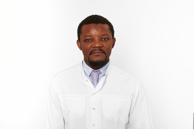 Serious black doctor man with small beard in white coat bright shirt isolated on white background