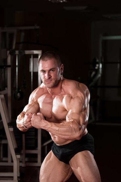 Serious Bodybuilder Standing In The Gym And Flexing Muscles