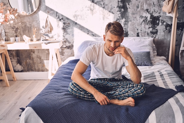 Serious brunette male person being deep in thoughts while being alone at home. Home concept