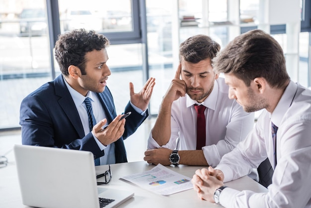 Serious business people sitting at table and discussing diagrams in office, business concept