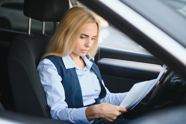 Serious business woman in the car examines important documents