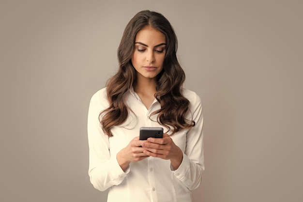 Serious business woman looking at the phone screen reading message on smartphone typing text on smart mobile phone Female freelancer chatting by mobile phone