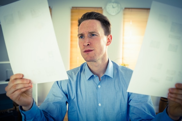 Photo serious businessman holding two paper sheets