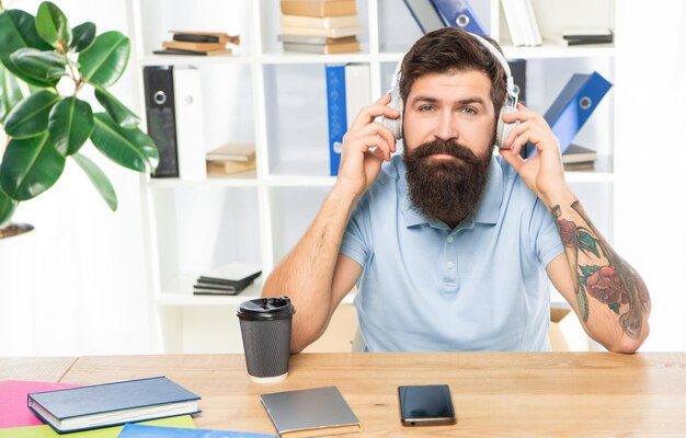 Photo serious businessman listening to melody in headphones in office music