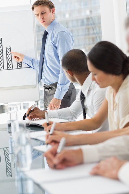 Serious businessman presenting bar chart in meeting