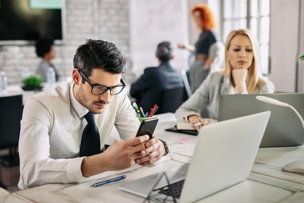 Serious businessman reading text message on mobile phone at work