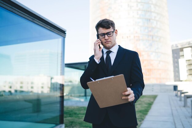 Serious businessman speaking on phone on street