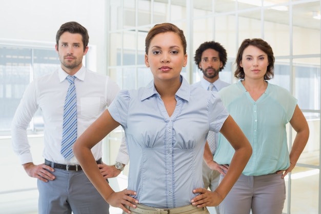 Serious businesswoman standing with colleagues