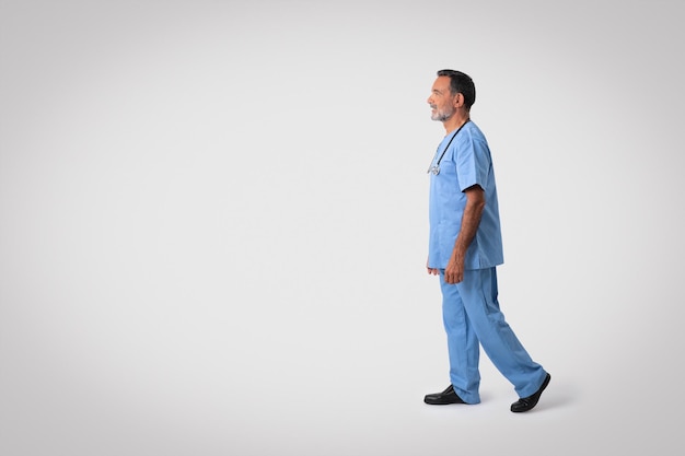 Serious caucasian senior doctor surgeon in blue uniform looking at empty space