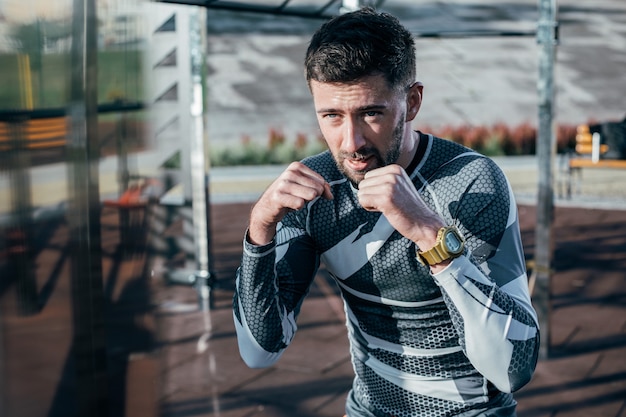 Serious concentrated boxer mastering his punches outdoors while training at the sports ground alone