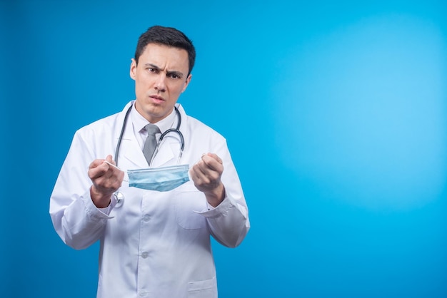 Serious doctor with medical mask in studio