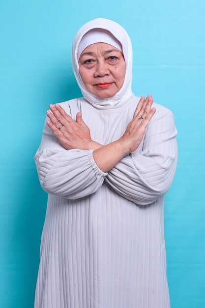 Serious elderly Asian woman in hijab crossed her arms saying no and expressing rejection gesture