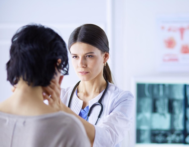 A serious female doctor examining a patient's lymph nodes