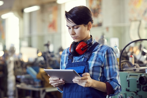 Serious female engineer using tablet in workshop