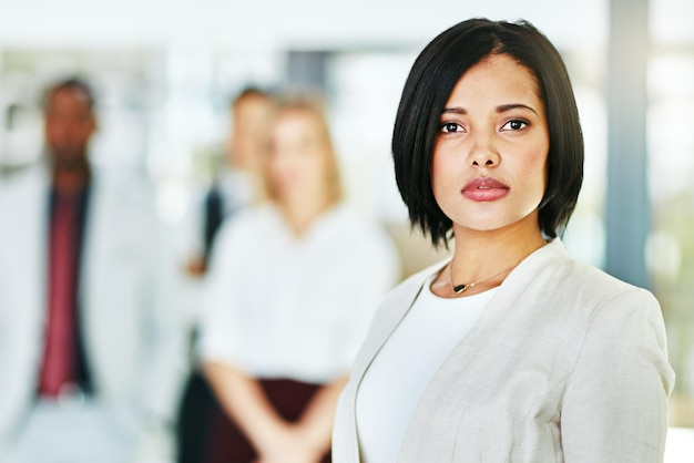 Serious focused and confident female lawyer looking at the camera and standing in her office with her team Portrait of a leader smart and intelligent attorney that is tough and resilient