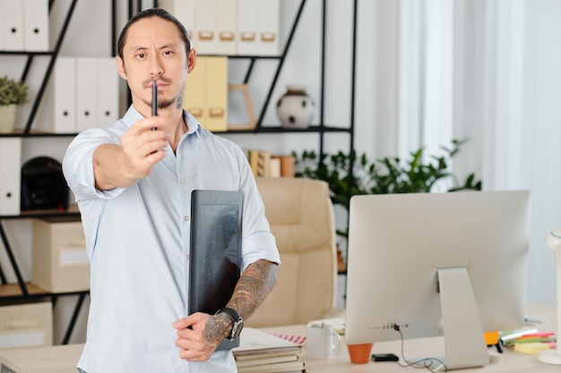 Serious frowning designer with graphic tablet looking at digital pen in his hand