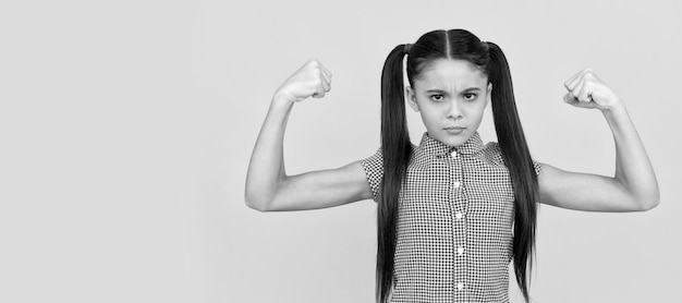 Serious girl child show strength gesture flexing arms yellow background girl power Child face horizontal poster teenager girl isolated portrait banner with copy space