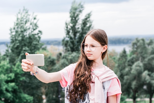 A serious girl in glasses takes a video selfie on a smartphone Content for social networks