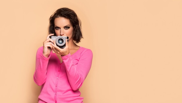 Photo serious girl photographing with photo camera beige background copy space photographer