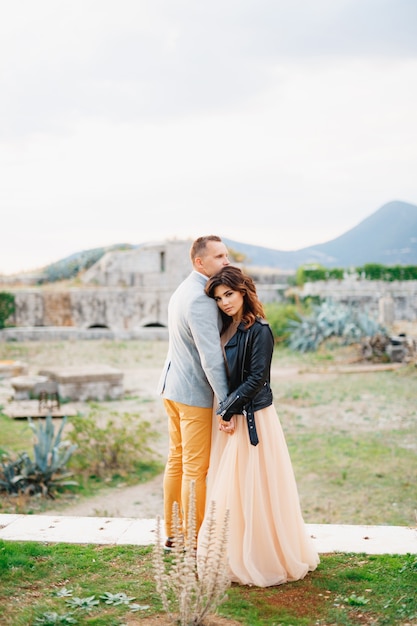 Serious groom and bride in a pastel wedding dress and a black leather jacket