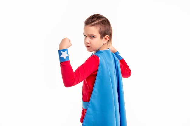 Serious little superhero kid looking at camera in white studio