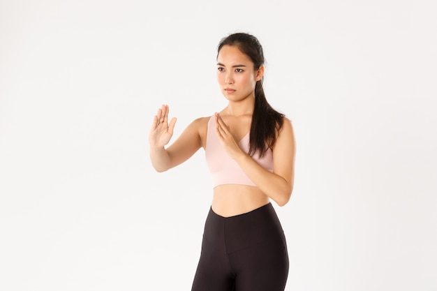   Serious-looking asian girl going to self-defense classes, standing in fighting, martial arts pose, wearing activewear for workout 