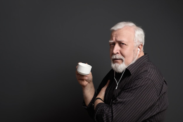 Serious man in headphones and with a cup in his hand