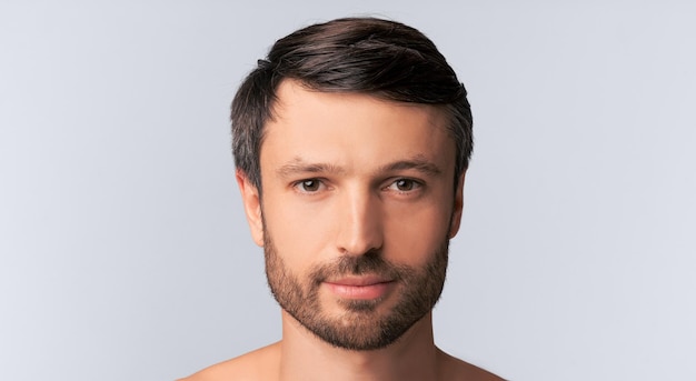 Photo serious man looking at camera posing over white background panorama