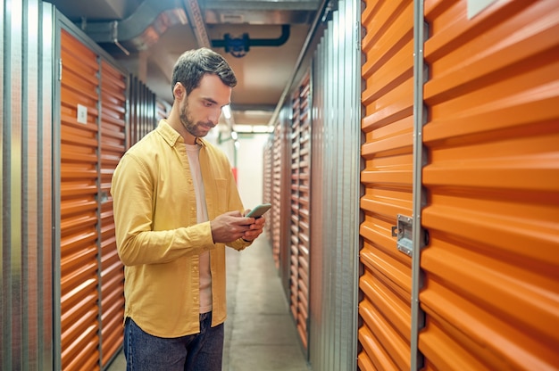 Serious man looking at smartphone in basement