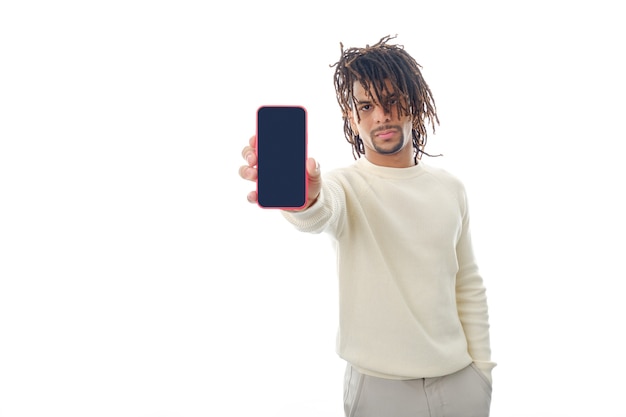 Serious man showing blank screen mobile phone to camera while standing on isolated background.